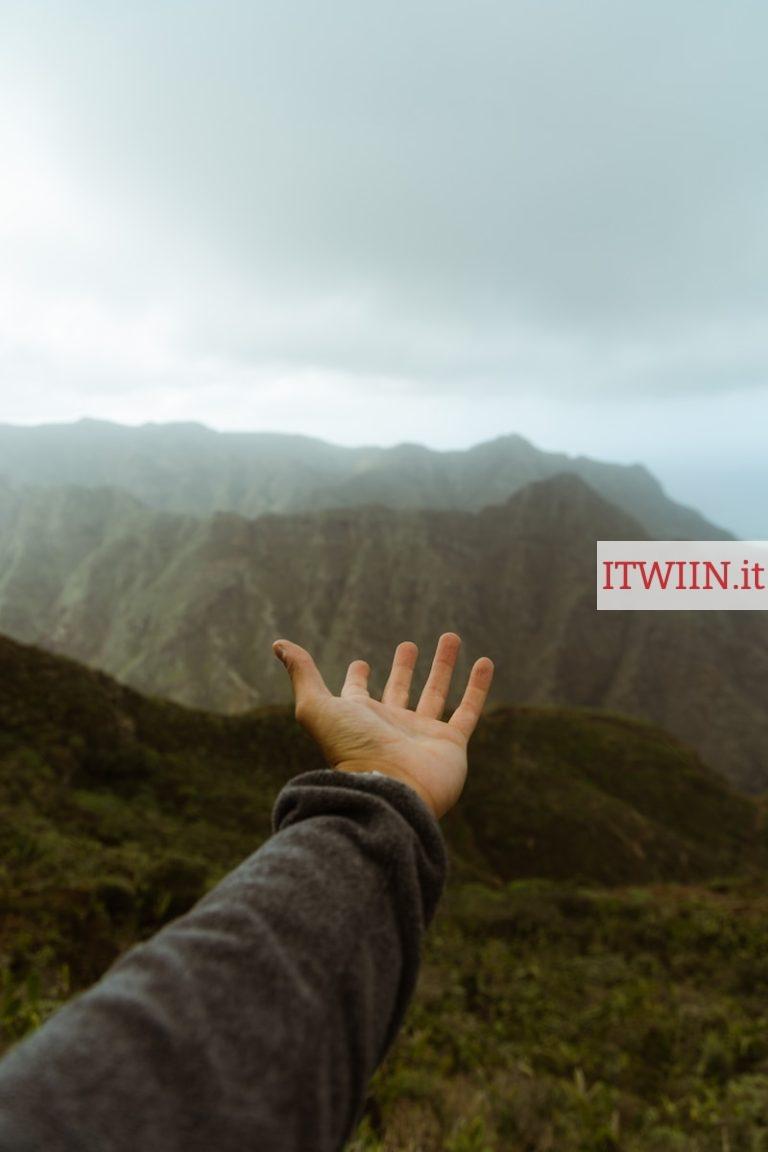a hand reaching out towards a mountain range