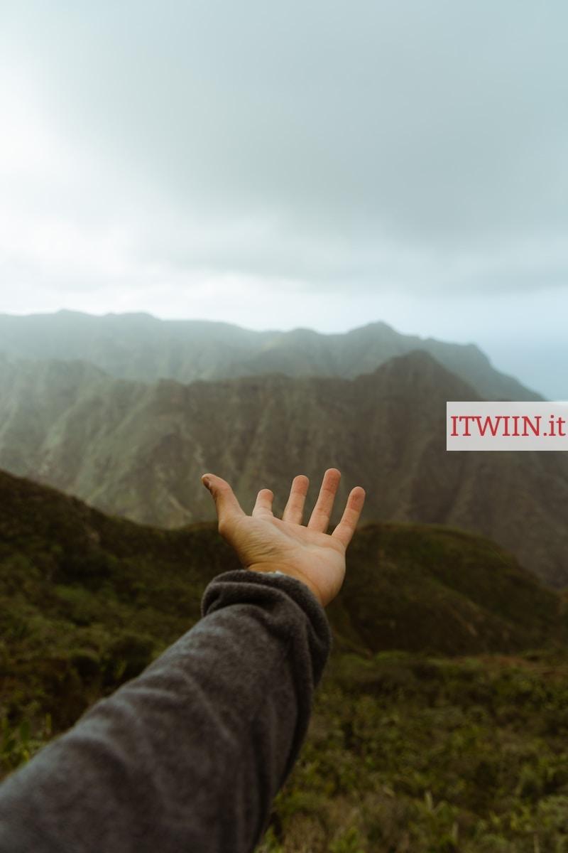 a hand reaching out towards a mountain range