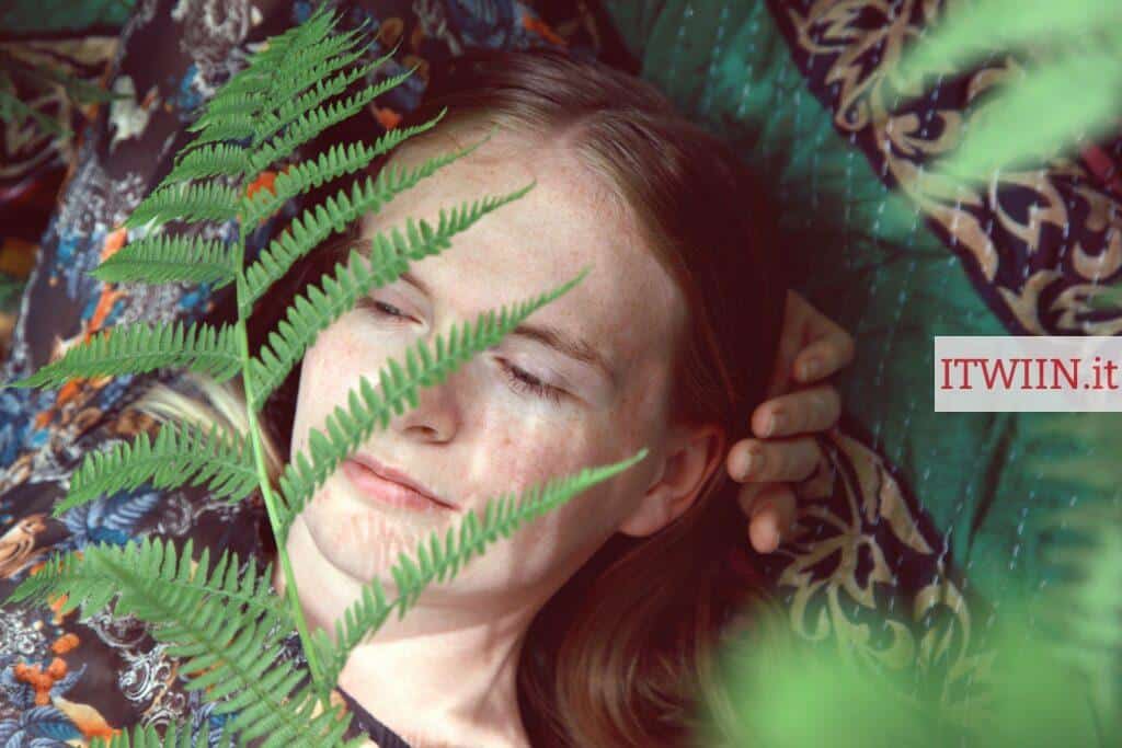 woman in white shirt lying on green leaves