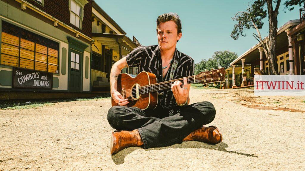 Man In Black Pants Sitting On Ground Playing Guitar