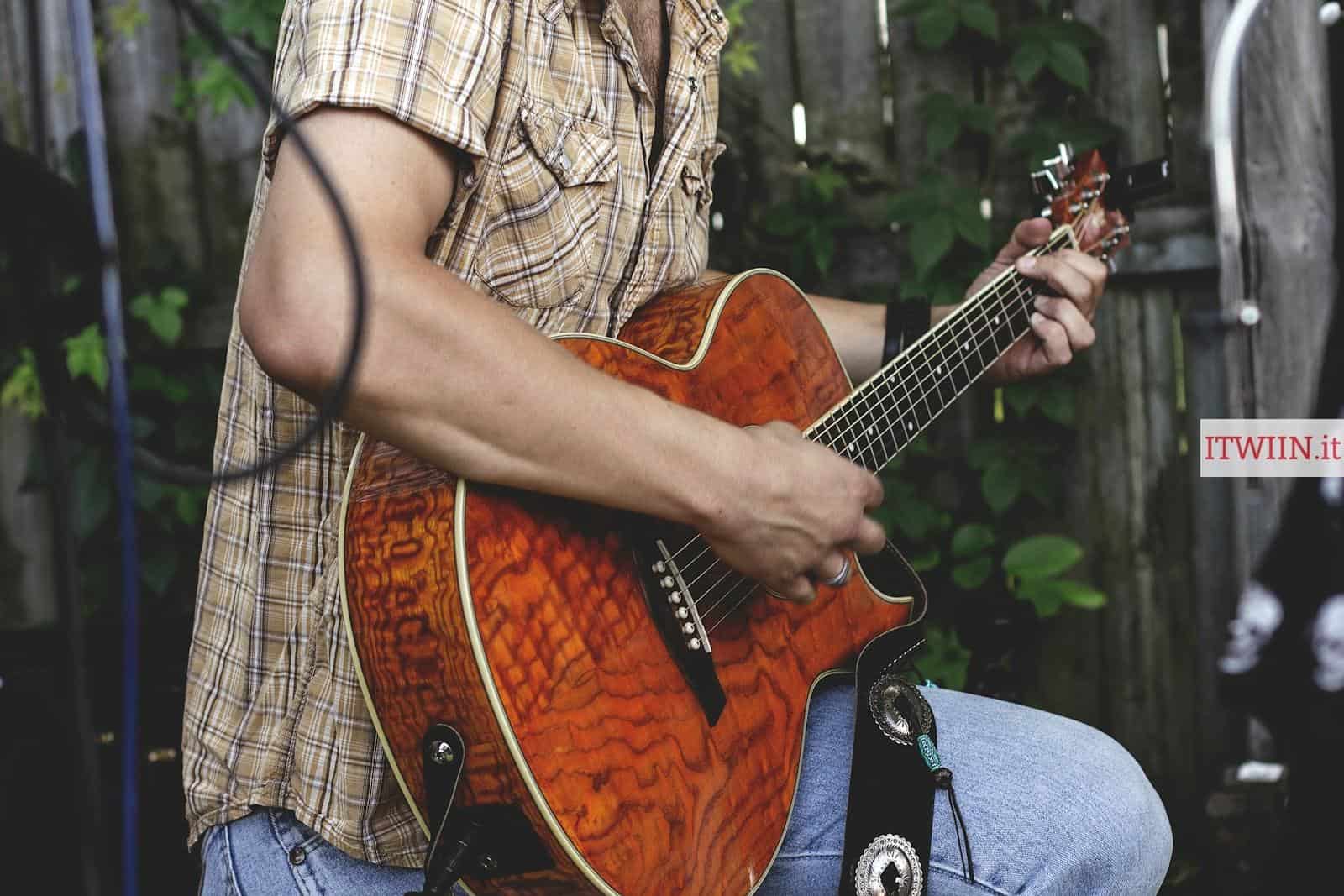 person holding brown guitar outdoor